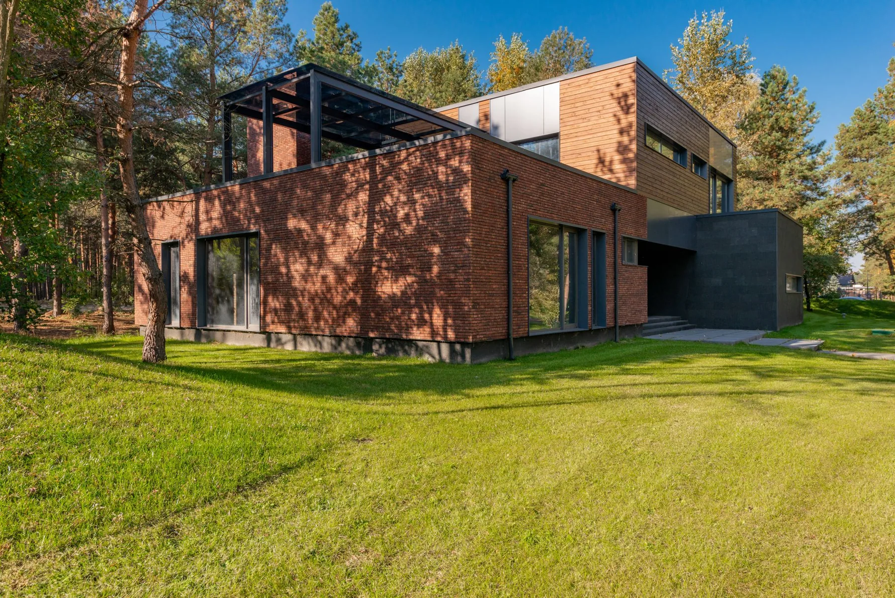 Contemporary brick and timber home surrounded by lawn and mature trees