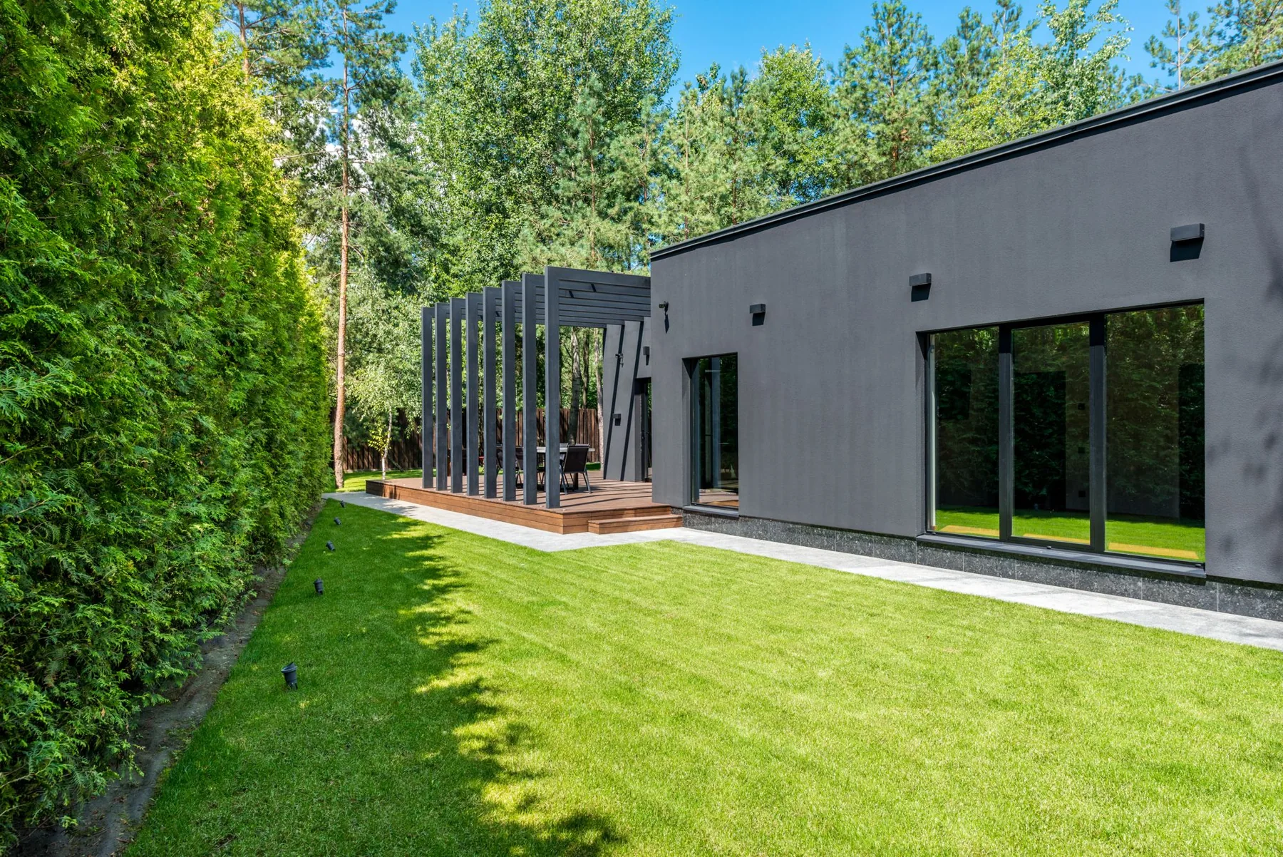 Landscaped lawn beside a contemporary home with decking and a pergola